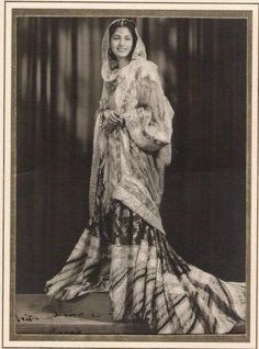 an old photo of a woman wearing a fur coat and dress with a veil on her head