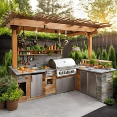 an outdoor kitchen with stainless steel appliances and potted plants on the outside wall, surrounded by greenery