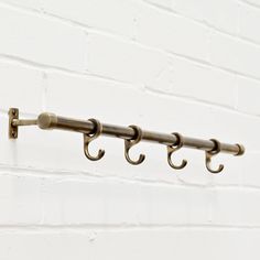 three metal hooks hang on a white brick wall