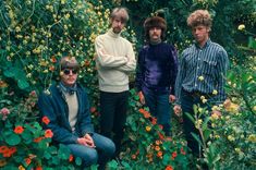 three men standing next to each other in front of flowers