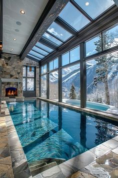 an indoor swimming pool in the middle of a room with large windows and a fireplace