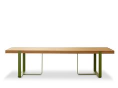 a wooden table with green metal legs and a white wall in the backround