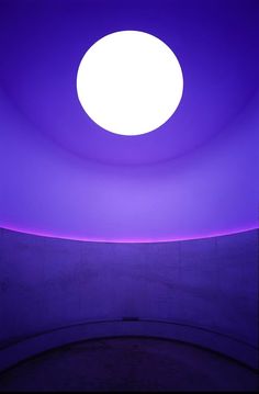 a person sitting on a bench under a purple light