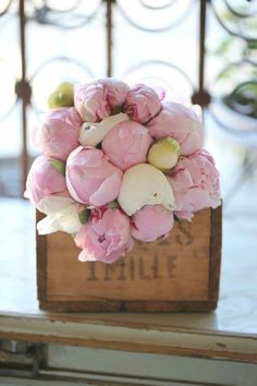 a bouquet of pink peonies in a wooden box on a table with the word smile written below it