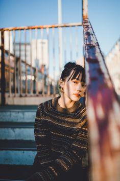 a woman is sitting on the steps with her hand under her chin and looking off into the distance