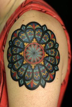 a woman's arm with a colorful tattoo design on the back of her shoulder