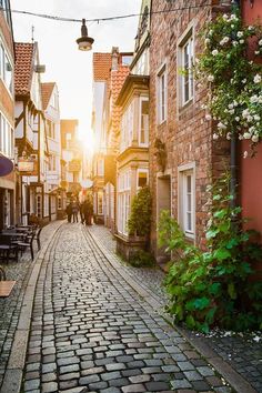 an old cobblestone street with people walking down it at sunset in the city