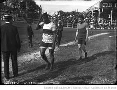 an old black and white photo of two women walking on the side of a field