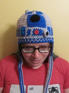 a woman wearing a crocheted hat with glasses and a red t - shirt