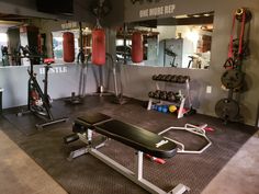 a gym room with equipment and mirrors in the background, including a bench, exercise balls, and punching bag