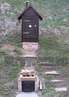 an outhouse in the middle of a field with steps leading up to it and a fire place