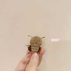 a hand holding a tiny stuffed animal in it's left hand with the word w87 on it