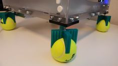 three tennis balls are attached to the back of a racket and stand on top of a table