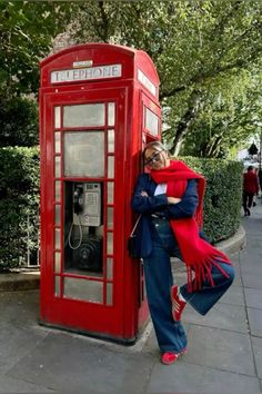 a woman leaning against a telephone booth on the sidewalk with her arms wrapped around her head