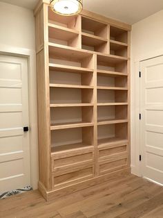 an empty bookcase in the corner of a room with wood floors and white walls