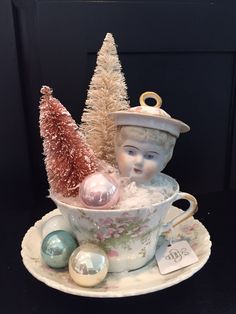 a tea cup with ornaments and a christmas tree in it