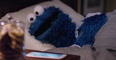 a cell phone sitting on top of a bed next to two blue stuffed animal heads