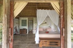 a bed sitting in the middle of a room under a white canopy over it's headboard