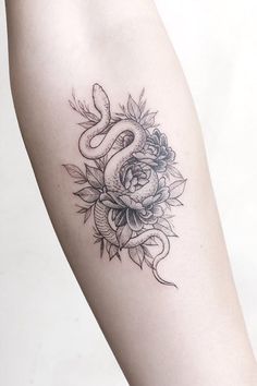 a woman's arm with a snake and roses tattoo on it, which is black and white