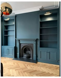 an empty living room with blue painted walls and wood flooring, built in bookshelves