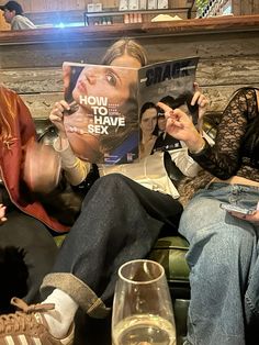 two women sitting on a couch reading magazines