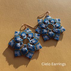 two small blue and white earrings on top of a table