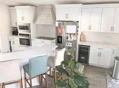 a kitchen with white cabinets and stainless steel appliances, along with a dining room table