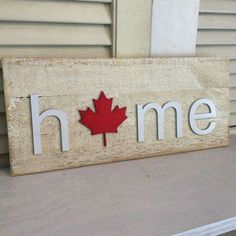 a wooden sign that says home with a red maple leaf on the front and side