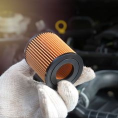 a close up of a person holding a air filter in front of a car engine