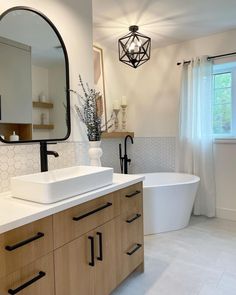 a bathroom with a large white tub next to a sink under a mirror and a wooden cabinet