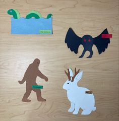 Cut paper cryptids on a wooden desk. Clockwise: the Loch Ness monster, mothman, a jackalope, and bigfoot. Halloween Door Decs, Door Dec Ideas, Door Dec Ideas Ra, College Door Decs Cricut, Door Decs Ra, Ra Dorm Door Decorations Name Tags, Doordecs Ra