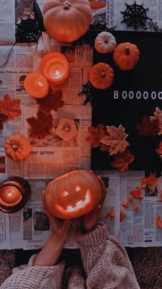 a person sitting in front of a pile of paper with candles and pumpkins on it