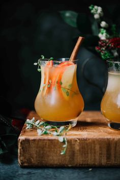 two glasses filled with drinks sitting on top of a cutting board next to each other