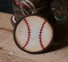 a baseball sitting on top of a piece of wood next to a vase filled with flowers