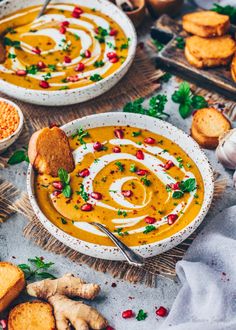 two bowls filled with soup next to crackers and other food on a table top