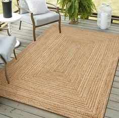 an outdoor area rug with chairs and potted plants