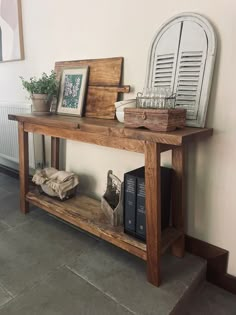 a wooden table with books and pictures on it next to a wall in a living room