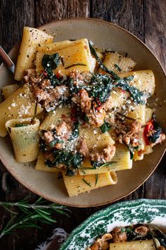 pasta with sausage, spinach and parmesan cheese in a bowl on a wooden table