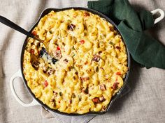 a skillet filled with macaroni and cheese on top of a cloth covered table