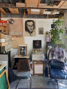 a room filled with furniture and pictures on the wall next to a chair in front of a potted plant