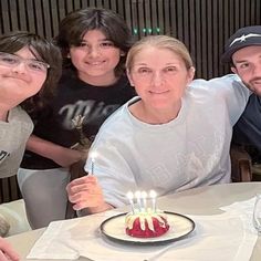 a group of people sitting at a table with a cake in front of them on a plate