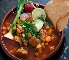 a bowl filled with lots of food next to a piece of tortilla on top of a table