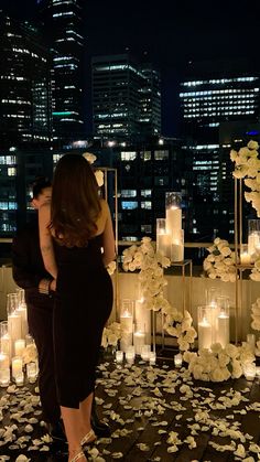 a man and woman standing next to each other in front of many lit up candles