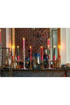 there are many candles on the mantle in front of the mirror and other decorations around it