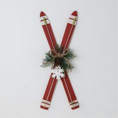 two red skis tied up to each other with snowflakes and evergreen branches