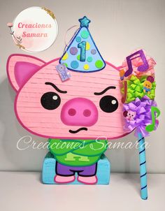 a pink pig with a party hat on it's head sitting next to a candy cane