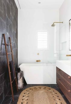 a bathroom with a rug, sink and bathtub next to a ladder on the wall