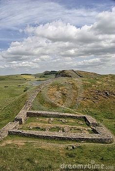 an ancient structure in the middle of a grassy field