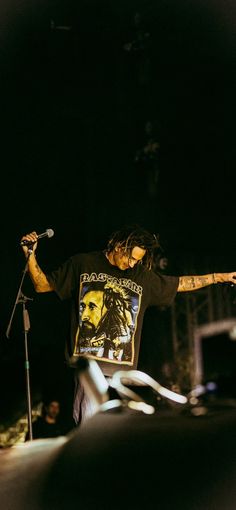 a man with dreadlocks standing in front of a microphone