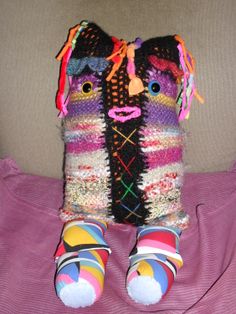 a stuffed animal is sitting on top of a pink bed sheet with colorful socks and slippers